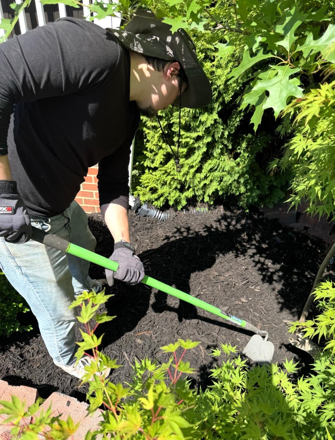 Caleb edging a fresh mulch bed by hand