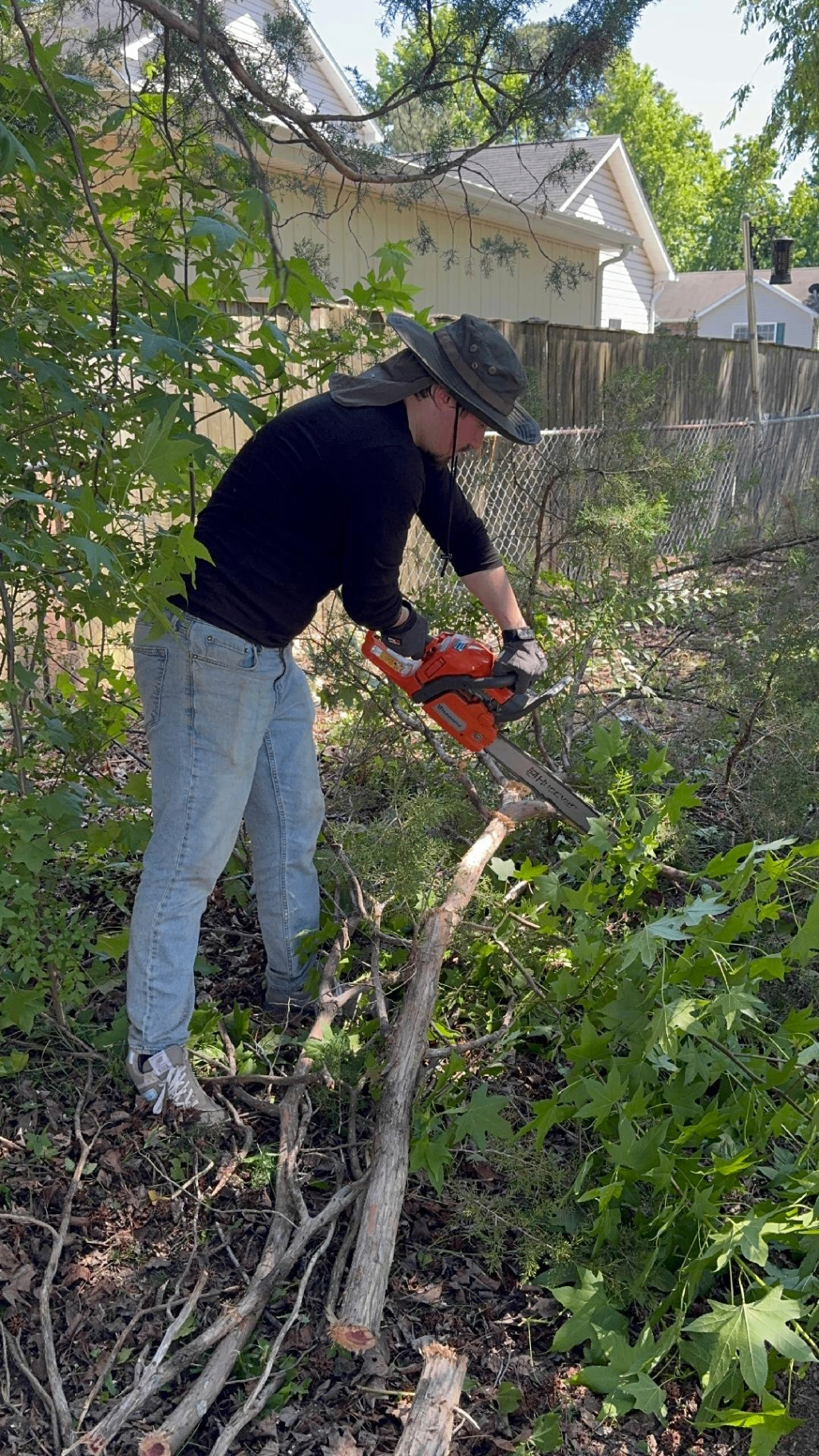 Caleb clearing overgrowth with a chainsaw